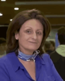 a woman wearing a blue shirt and a blue scarf smiles for the camera