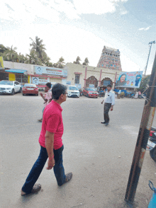 a man in a red shirt walks down a street in front of a building that says ' shree ram mandir '