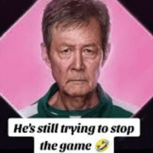 a man is standing in front of a pink background and a sign that says `` he 's still trying to stop the game ''