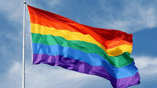 a large rainbow flag is flying in the wind