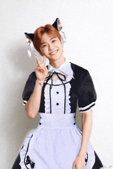 a young man in a maid costume with cat ears on his head giving a peace sign