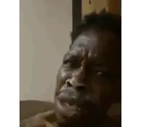 a man with a beard is making a funny face with his mouth open while sitting on a couch .