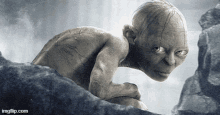 a gollum from the lord of the rings is crawling on a rock .