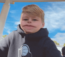 a young boy is making a funny face while wearing a hoodie .