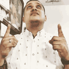 a man wearing a white shirt with black anchors on it gives a thumbs up