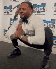 a man squatting in front of a wall with power 105.1 on it