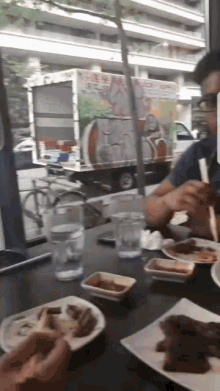 a man is sitting at a table with plates of food in front of a truck that says coca cola