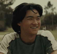 a young man in a green and white shirt smiles