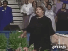 a woman in a black dress is standing in front of a crowd of people in a church .