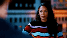 a woman in a colorful striped sweater is standing in front of a plane .