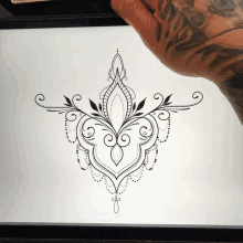 a person with a tattoo on their arm is drawing a floral design