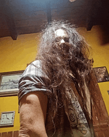 a man with long hair and a harley davidson shirt stands in front of a clock