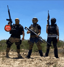 a group of soldiers are standing in the dirt holding guns and one of them is wearing a mask