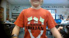 a boy wears a red shirt that says kiefer trojan on it