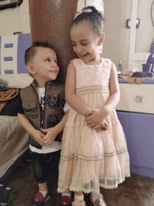 a little girl in a pink dress stands next to a little boy wearing a jacket that says jeep on it