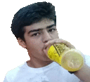 a young man is drinking a drink from a yellow bottle .