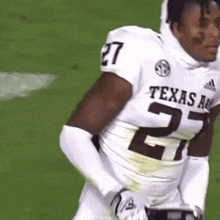 a football player wearing a texas a & m jersey is standing on a field with his hands on his hips .