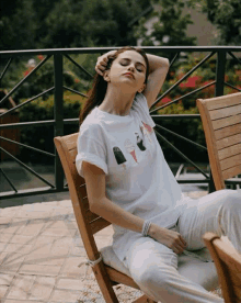 a woman wearing a white t-shirt with ice cream cones on it sits in a chair with her eyes closed