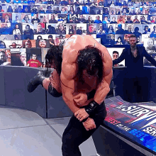 a wrestler is carrying another wrestler on his shoulders in front of a sign that says the best of the best