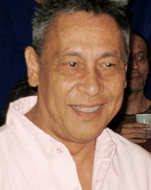 a man in a pink shirt is smiling and looking at the camera