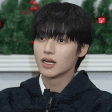 a close up of a young man 's face in front of a christmas tree .