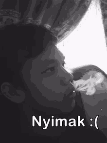 a black and white photo of a person smoking with the caption " nyimak "