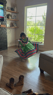 a little girl in a green dress is dancing in front of a window