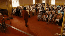 a woman in a red dress stands in front of a crowd of people in a church with the words bounty on the bottom