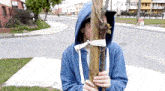 a man in a blue hoodie is holding a tree branch