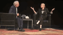 a man and a woman are sitting in chairs on a stage .