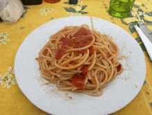 a plate of spaghetti with tomato sauce on a yellow table cloth