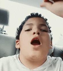 a young boy is making a funny face while sitting in a car .