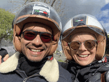 a man and a woman wearing helmets and sunglasses smile for a picture