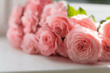 a bunch of pink roses are sitting on a window sill