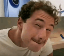 a man is making a funny face with his eyes closed .