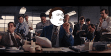 a man in a suit and tie is sitting at a desk with a cartoon face on his face