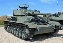 a green tank is parked on gravel in a gravel area .