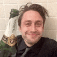 a man in a suit and tie is holding a bottle of champagne in his hand .