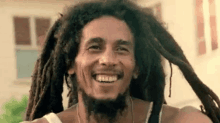 a close up of a man with dreadlocks and a beard smiling .