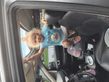 a little girl wearing a shirt that says strong is sitting in the back seat of a car