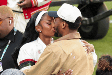 a man wearing a white hat that says ' tommy hilfiger ' on it kisses a woman