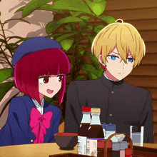 a boy and a girl are sitting at a table with bottles of sauces