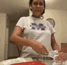 a woman wearing a mater bay t-shirt prepares food