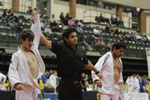 a referee in a black shirt holds up a man 's fist in the air