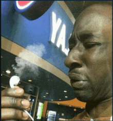 a man smoking a cigarette in front of a sign that says ya