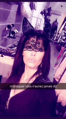 a woman wearing a lace mask and bunny ears takes a selfie with a caption in french