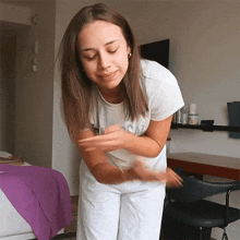 a woman wearing a white shirt that says ' i love you ' on it is standing in a room