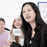 a woman holds up a sign that says 1000 on it