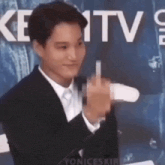 a man in a suit and tie is giving the middle finger at a microphone .