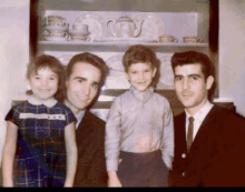 a group of people posing for a picture in front of a cabinet with plates and cups